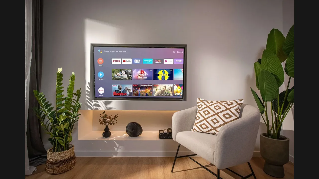 A wall-mounted smart TV showing streaming app rows above a media console, beside an armchair